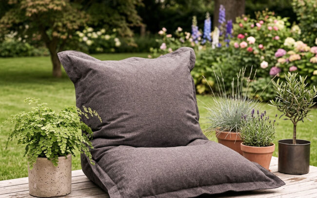 Ai foto af Nice sækkestol i sort stof på en træterrasse med krukker med planter og træer og græsplæne og træer i baggrunden genereret til Saekkestolen.dk / Heimili af freelance marketing konsulent og marketingkonsulent Marketingsnedkeren